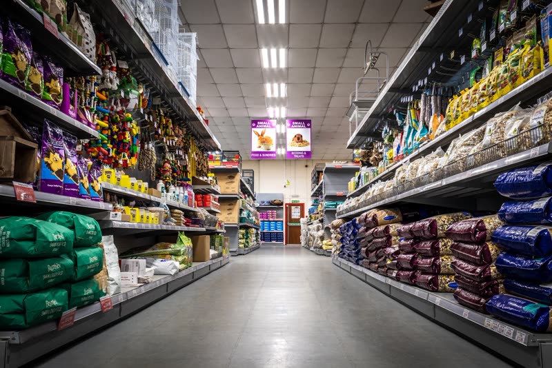 Inside the shop, looking down an aisle stacked floor to ceiling with pet food and accessories